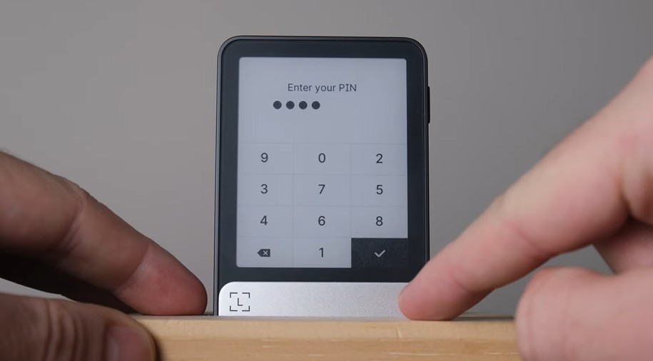 Ledger Flex Hardware Wallet aufgeklappt auf einem Holztisch mit Monero-Münze im Hintergrund