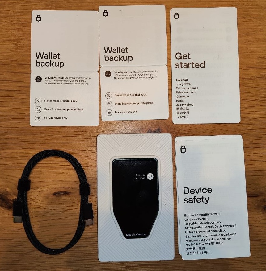 Lieferumfang des Trezor Safe 7 mit Hardware Wallet, USB-C-Kabel, Backup-Karten und Sicherheitsanleitungen.