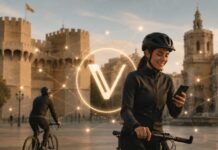 Bikademy bringt VeChains B3TR-Token auf Valencias Radwege Radfahrerin in Valencia vor historischem Stadttor mit zentral eingeblendetem VeChain-Logo und digitalem Netzwerk.
