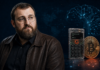 Cardano-Gründer Charles Hoskinson neben einer Coldcard-Hardware-Wallet und einer Bitcoin-Münze vor einem digitalen KI-Hintergrund.