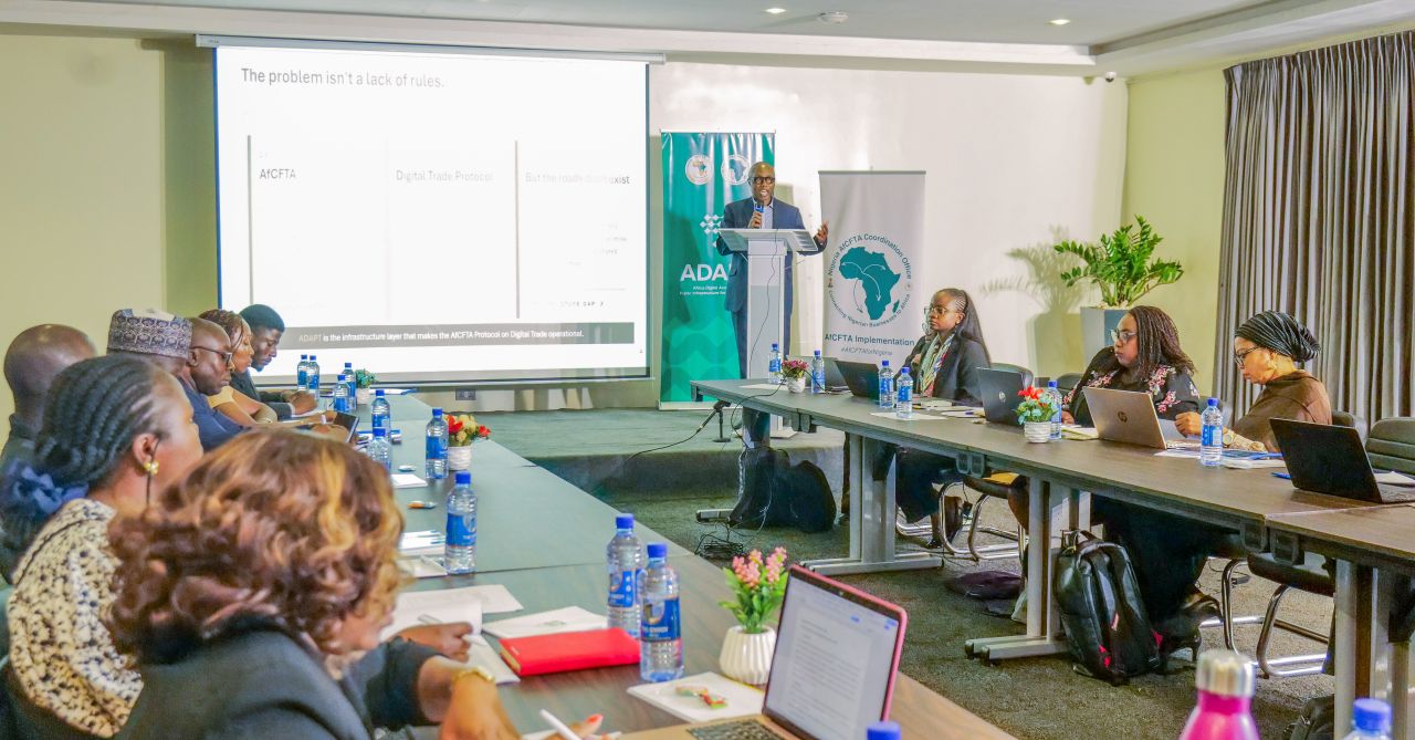 Fachveranstaltung zur Umsetzung von IOTA ADAPT in Nigeria mit Vortrag und Teilnehmenden an Konferenztischen.