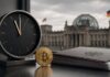 Krypto-Haltefrist auf der Kippe? 12. August wird zum Stichtag für Klingbeil Bitcoin vor dem Reichstag mit Uhr als Symbol für den Zeitdruck bei der Krypto-Steuer