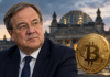 Krypto-Haltefrist: Auch Armin Laschet zweifelt an geplanter Abschaffung Armin Laschet neben einer goldenen Bitcoin-Münze vor dem Reichstagsgebäude.