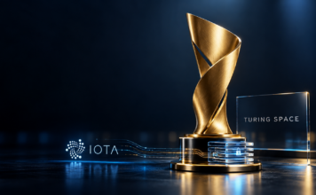 Symbolische Trophäe mit Turing-Space-Schriftzug und IOTA-Emblem vor dunkelblauem Hintergrund