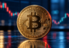 Goldene Bitcoin-Münze vor einem unscharfen Kurschart mit roten und grünen Kerzen auf dunkelblauem Hintergrund.