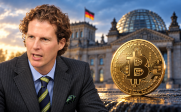 Krypto-Haltefrist: CDU-Finanzpolitiker stellt sich gegen Klingbeils Steuerpläne Olav Gutting neben einer goldenen Bitcoin-Münze vor dem Reichstagsgebäude.