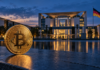 Goldene Bitcoin-Münze vor dem Bundeskanzleramt in Berlin bei Abendlicht.