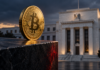 Goldene Bitcoin-Münze auf einer dunklen Kante vor dem Gebäude der US-Notenbank Federal Reserve.