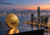 Goldener Bitcoin vor der Skyline Hongkongs bei Dämmerung