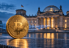Bundestag beschließt Bitcoin-Datenaustausch: Finanzamt erhält vollen Zugriff Goldene Bitcoin-Münze vor dem Reichstagsgebäude mit blauen Datenströmen als Symbol für den Austausch von Krypto-Steuerdaten.