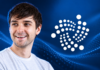 Illustration von Dominik Schiener neben dem IOTA-Logo vor blauem Hintergrund