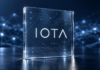 IOTA aktiviert Protokoll 38: Das bringt das neue Mainnet-Update IOTA-Schriftzug auf einer Glasplatte vor einem blauen Netzwerk aus verbundenen Knoten.