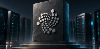 IOTA verdreifacht Validator-Hürde: Künftig sind 6 Millionen Token nötig Silbernes IOTA-Symbol auf einem erhöhten dunklen Sockel vor Serveranlagen.
