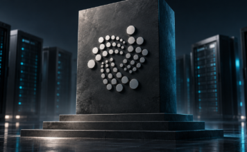 IOTA verdreifacht Validator-Hürde: Künftig sind 6 Millionen Token nötig Silbernes IOTA-Symbol auf einem erhöhten dunklen Sockel vor Serveranlagen.