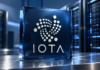 IOTA veröffentlicht neues Update: Protokoll 38 bringt wichtige Änderungen Weißes IOTA-Logo auf einer blauen Glasplatte vor Serverracks.