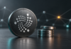 IOTA plant Validator-Strafen: Fehler könnten die gesamte Belohnung kosten IOTA-Logo auf einer dunklen Münze neben metallischen Scheiben als Symbol für Validator-Belohnungen.