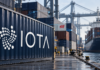 IOTA: Virtual Watch Tower startet offiziell – H&M ist dabei Symbolische Hafenansicht mit IOTA- und H&M-Logos auf Containern und blauen Datenverbindungen.