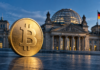 Goldene Bitcoin-Münze vor dem Berliner Reichstagsgebäude als Symbol für die Debatte um die Krypto-Haltefrist.