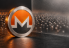 Silberne Monero-Münze vor einer Milchglasscheibe und zahlreichen kleinen Metallkugeln auf dunklem Hintergrund.