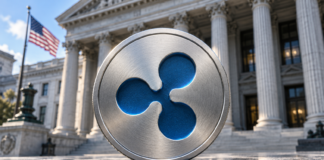 BREAKING: Ripple erhält Bankzulassung in den USA – historischer Meilenstein erreicht Silbernes Medaillon mit blauem Ripple-Logo vor einer Bankfassade mit US-Flagge.