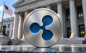 BREAKING: Ripple erhält Bankzulassung in den USA – historischer Meilenstein erreicht Silbernes Medaillon mit blauem Ripple-Logo vor einer Bankfassade mit US-Flagge.