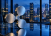 Ripple zündet die nächste Stufe: Neue KI-Funktionen und Renditen rund um die Uhr Silbernes Ripple-Logo auf einem Konferenztisch vor einer beleuchteten Skyline am Abend.