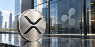 Silberne Münze mit XRP-Symbol vor einer Glasfassade mit Ripple-Logo.