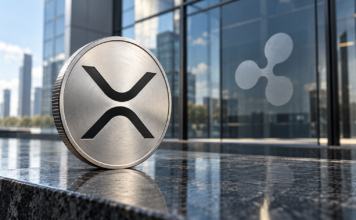Ripple-CEO Garlinghouse mit klarer Ansage: „Wir werden XRP niemals aufgeben“ Silberne Münze mit XRP-Symbol vor einer Glasfassade mit Ripple-Logo.